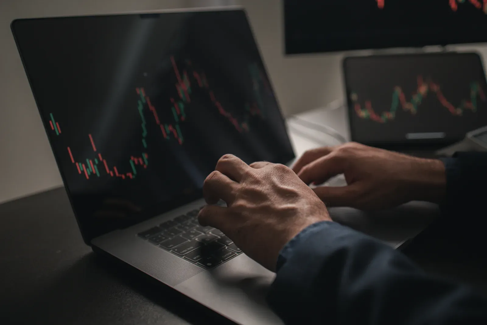 Hands on a laptop showing candlestick trading charts