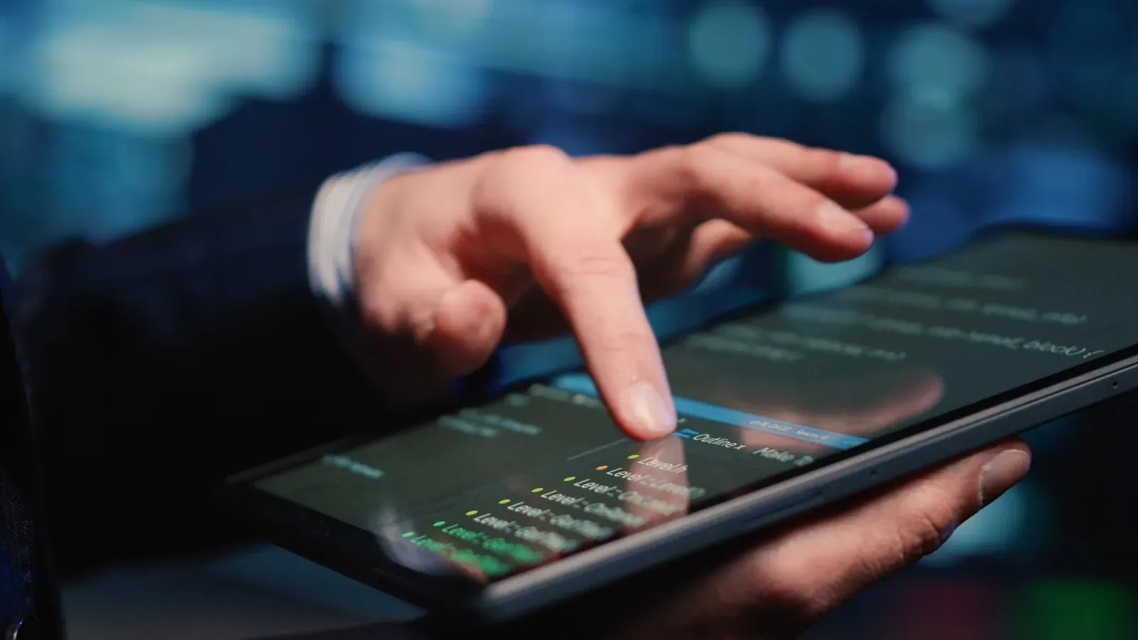 Hand pointing at a tablet showing a market data table at night