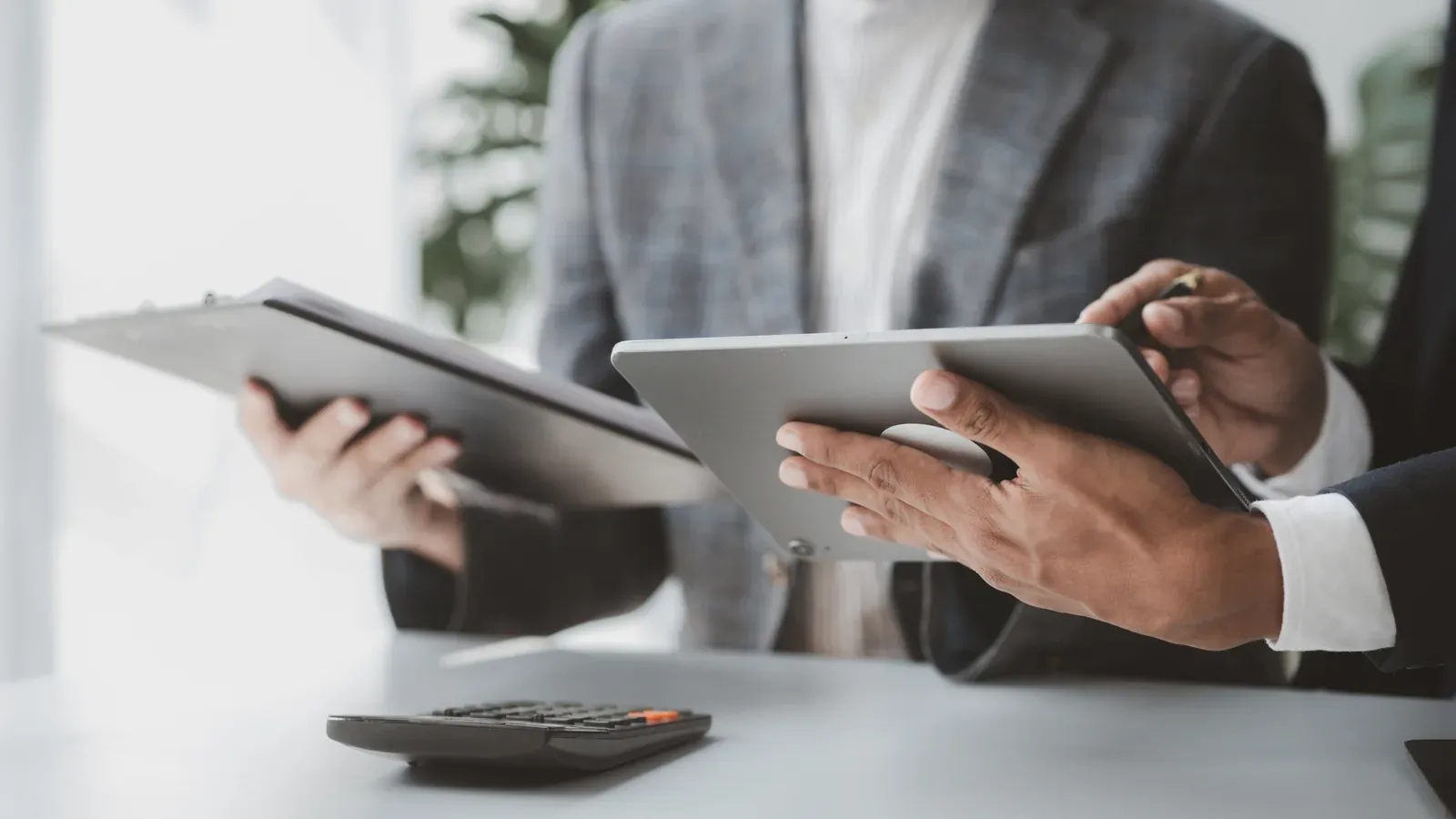 Two colleagues comparing tablets in a bright office